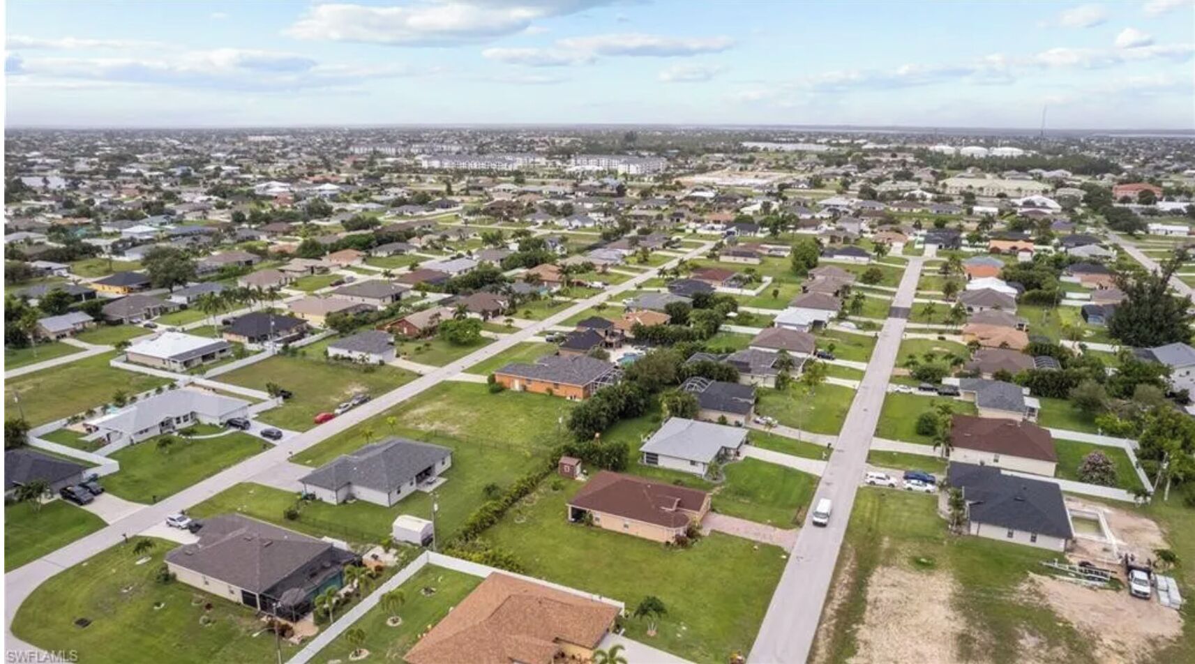 A residential area with houses arranged in a grid pattern, featuring front yards and driveways.