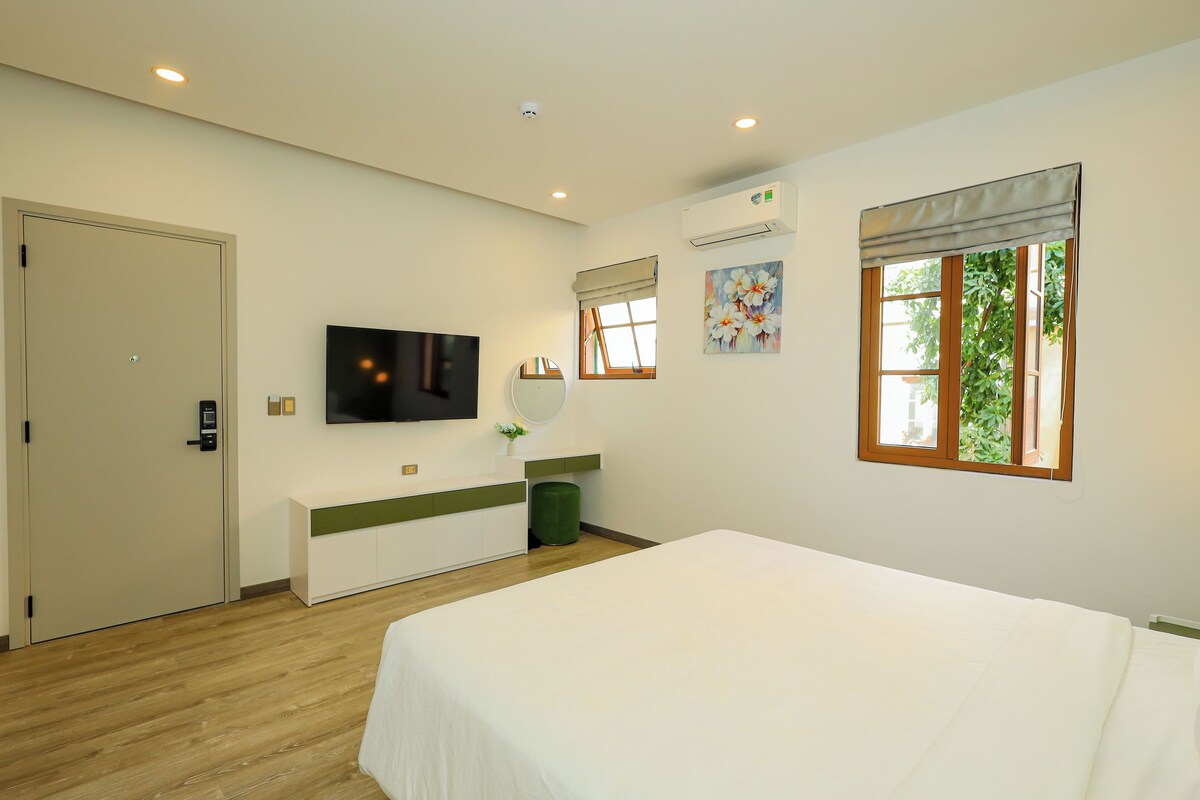 Ein Hotelzimmer mit Bett, Fernseher, Spiegel, Fenster mit Blick und Tür.