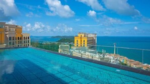 Una piscina con vista despejada al océano y edificios al fondo.