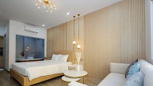 Una habitación de hotel moderna con una cama grande, un sofá, una mesita y un espejo.