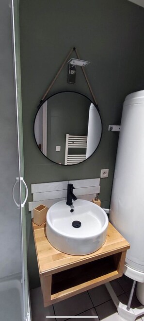 A bathroom with a round mirror, a white sink, and a toilet.
