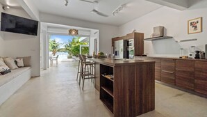 Una cocina moderna con una isla central, armarios de madera y vistas a una piscina y palmeras.