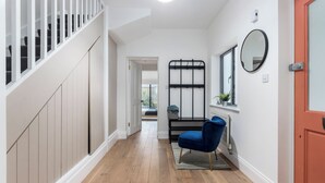 A hallway with a wooden floor, a blue chair, a radiator, and a red door.