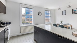A modern kitchen with white cabinets, a large island, and a dining area with a table and chairs.
