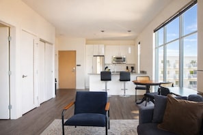 Un appartement moderne doté d’une cuisine, d’un coin repas et de grandes fenêtres.