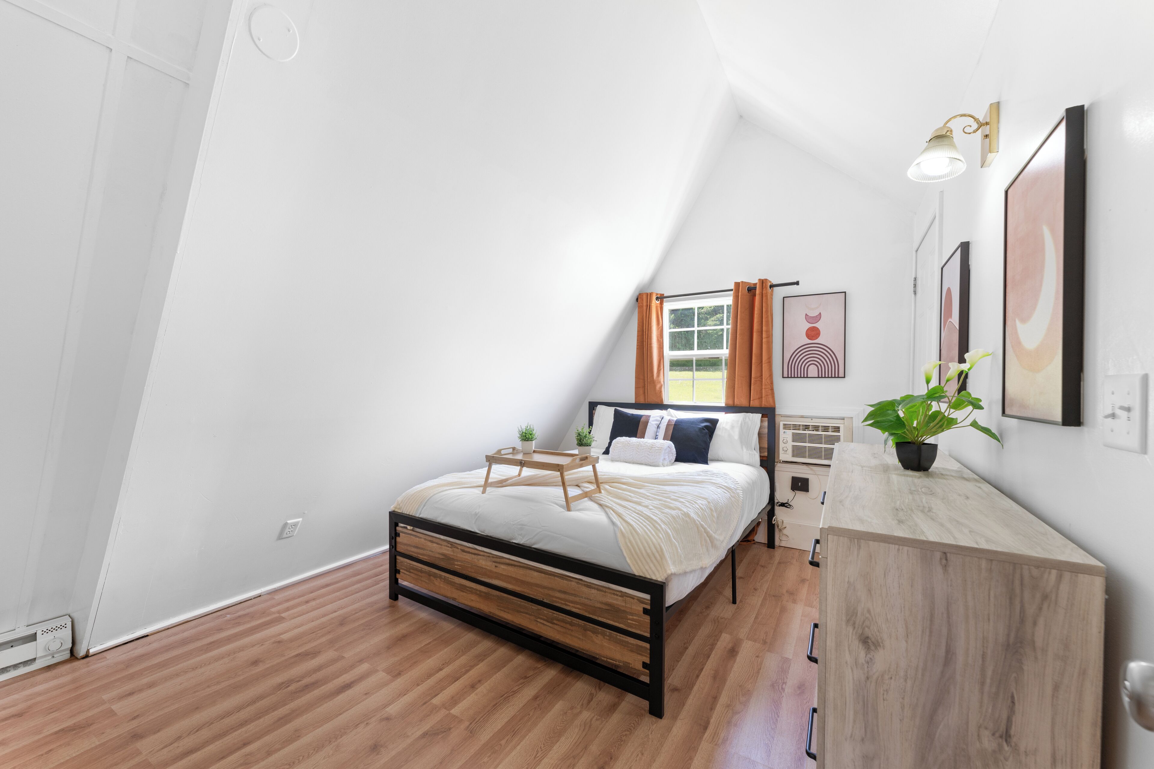 A bedroom with a bed, bedside table, and a potted plant.