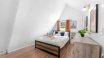 A bedroom with a bed, bedside table, and a potted plant.