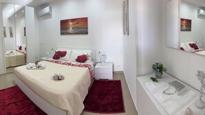 Een moderne slaapkamer met een bed, nachtkastjes, een spiegel en kunstwerken aan de muur.