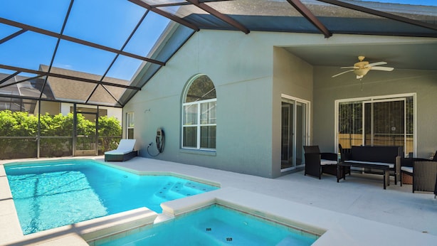 A covered outdoor swimming pool with a ceiling fan, lounge chairs, and a patio area. - Highgate@Legacy Park, a 3 bed 2 bath pet friendly home within a gated community (Davenport)