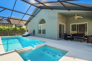 Une piscine extérieure couverte, dotée d’un ventilateur de plafond, de chaises longues et d’un espace patio.