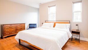 A bedroom with a wooden bed, a dresser, and two windows.