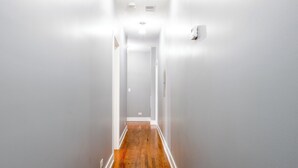 A narrow hallway with wooden flooring and white walls.