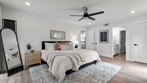 A bedroom with a bed, bedside tables, a mirror, a ceiling fan, and a door leading to a bathroom. - COMPLETELY REMODELED 3 BDR, 2 Bath, Golf Course View Condo (Pinehurst)