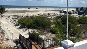 A beach view with a wooden boardwalk, beach huts, and a lifeguard tower.