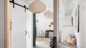 A modern interior with a minimalist design, featuring a hallway leading to a dining area with a round table and chairs.