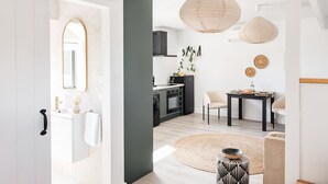A modern kitchen with a dining area, a round rug, and a small side table.