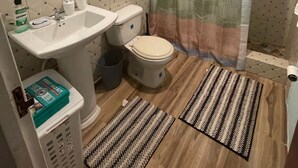 A bathroom with a toilet, sink, and shower curtain. -  2 bedrooms, 1 bathroom, kitchen, WiFi, and AC in Greendale, Spanish Town. (Spanish Town)