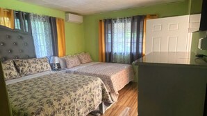 A room with two beds, a wooden floor, a ceiling fan, and a white door. -  2 bedrooms, 1 bathroom, kitchen, WiFi, and AC in Greendale, Spanish Town. (Spanish Town)