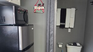 Une cuisine de taille réduite équipée d’un réfrigérateur, d’un four à micro-ondes et de placards.