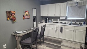 Une cuisine moderne avec des meubles blancs, une table à manger avec des chaises, une machine à café et une fenêtre avec un rideau.