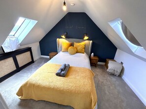 Cozy attic bedroom with a large bed, nightstands, and a decorative sign above.
