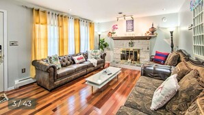 A living room with a brown leather sofa, a patterned rug, and a fireplace. - Relaxing 5-Bedroom Getaway with Saltwater Pool & Game Room Close to Hershey (Palmyra)