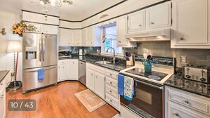 A modern kitchen with white cabinets, stainless steel appliances, and a granite countertop. - Relaxing 5-Bedroom Getaway with Saltwater Pool & Game Room Close to Hershey (Palmyra)