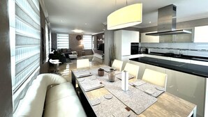 Een moderne keuken met een eethoek, met een groot schiereiland, moderne apparatuur en een minimalistisch design.