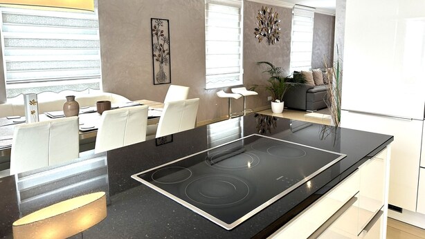Een moderne keuken met een zwart aanrecht, witte kastjes en een ingebouwde kookplaat.