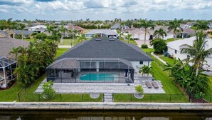 A modern house with a swimming pool, surrounded by a well-maintained lawn and palm trees.