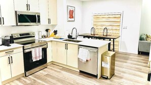 A modern kitchen with stainless steel appliances, a built-in oven, a microwave, and a sink. - Modern Marvel in Windermere (Edmonton)