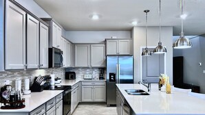 Una cocina moderna con electrodomésticos de acero inoxidable, armarios blancos y una isla grande con un lavamanos.