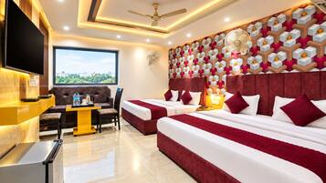 A hotel room with a large bed, a sofa, a desk with a flat-screen TV, and a city view.