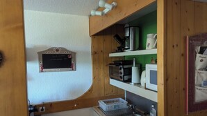 Eine kompakte Küche mit Kaffeemaschine, Toaster und Mikrowelle auf Holzböden, einem kleinen Spülbecken und einer Tafel mit Herzdesign.