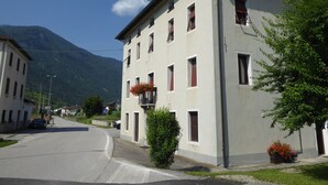 A two-story building with a flat roof, multiple windows, and a balcony with red flowers. - Apartment With Garden, Del Corlo Lake, Belluno (Arsiè)