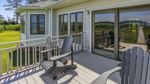 A covered deck with Adirondack chairs, a glass door leading to a grassy area, and a small building with shutters. - "Endless Summer" Waterfront on the Chesapeake Bay! (Woolford)