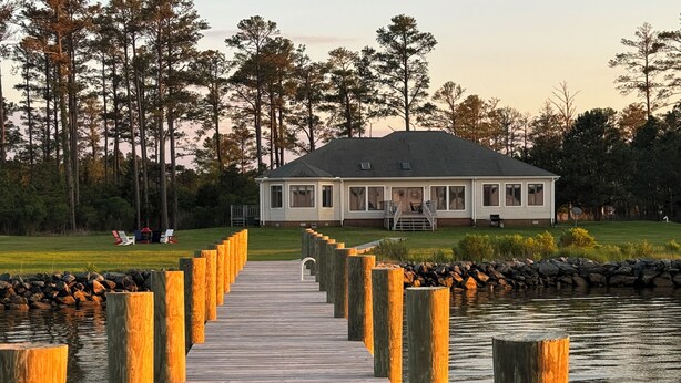 A wooden pier leading to a house with a deck and outdoor seating area, surrounded by trees and a body of water. - "Endless Summer" Waterfront on the Chesapeake Bay! (Woolford)