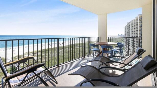 A balcony with a view of the beach and ocean, furnished with lounge chairs and a small table. - Phoenix 8 8904- Sand Shells Sun Can Rent at 18 3 Bedrooms 2 Baths (Orange Beach)