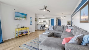 A living room with a gray sectional sofa, a yellow console table, and a colorful rug. - Phoenix 8 8904- Sand Shells Sun Can Rent at 18 3 Bedrooms 2 Baths (Orange Beach)