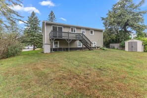 A two-story house with a front deck and a small shed.