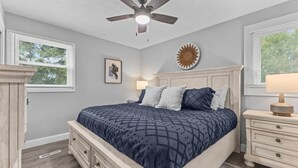 A bedroom with a bed, a ceiling fan, a nightstand, a lamp, and a wall decoration. - Cute 3BR APT - So Burlington (South Burlington)