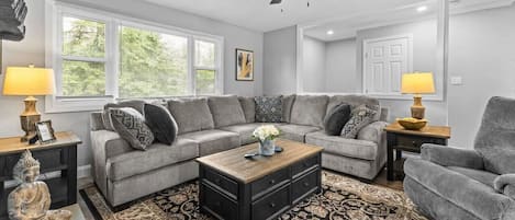 A living room with a sectional sofa, a coffee table, and a ceiling fan.