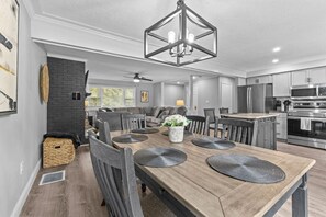 A modern kitchen with a central island, stainless steel appliances, and a dining area with a wooden table and chairs.