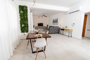 Una sala de estar moderna con un sofá gris, una mesa de centro de madera y un televisor.