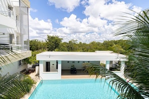 Un edificio moderno con piscina, rodeado de vegetación y palmeras.