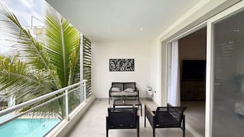 Un balcón con piscina, un sofá, dos sillas y un adorno de pared.