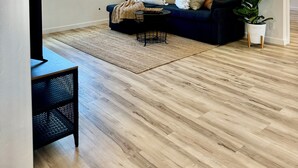 Una sala de estar con un sofá azul oscuro, un ventilador de techo, un espejo grande y una planta en maceta.