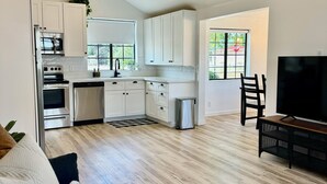 Una cocina moderna con armarios blancos, electrodomésticos de acero inoxidable y un ventanal amplio.