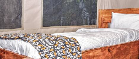 A wooden bed with white bedding and a patterned throw blanket.