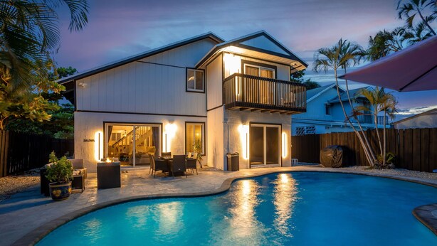 A two-story house with a swimming pool, outdoor seating, and a balcony.
